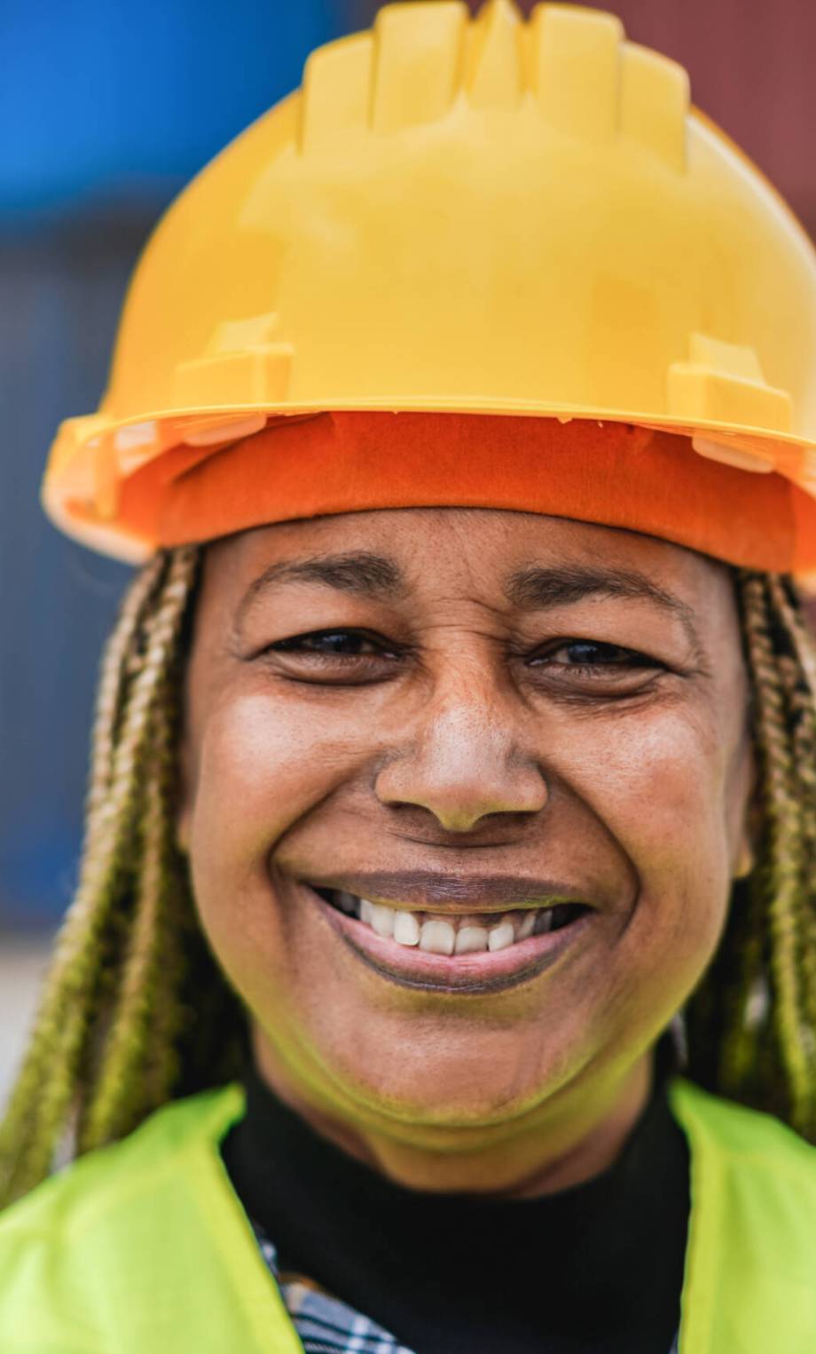 Worker African senior woman smiling on camera with industrial port on background - Main focus on nose
